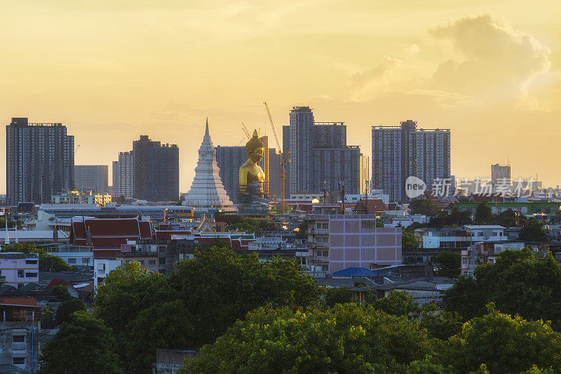 鸟瞰图，在日落时分，在Wat Paknam Bhasicharoen寺的大金佛雕像和住宅建筑，泰国曼谷市未来的地标。